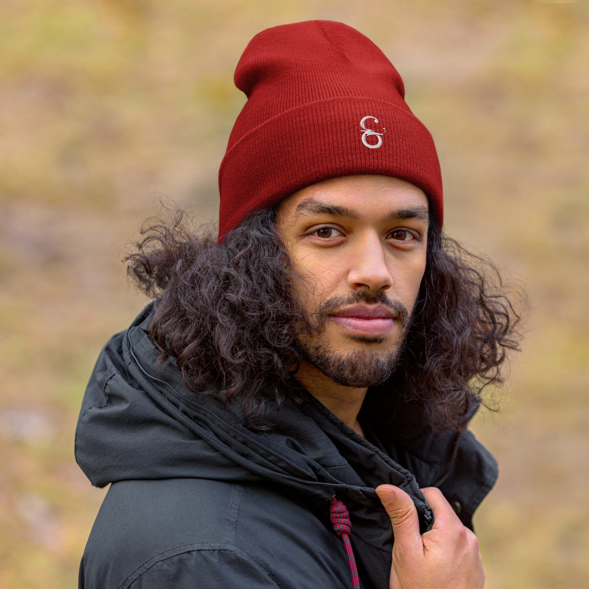 Hombre vistiendo el gorro unisex de punto en color rojo, destacando su borde vuelto y ajuste ceñido.